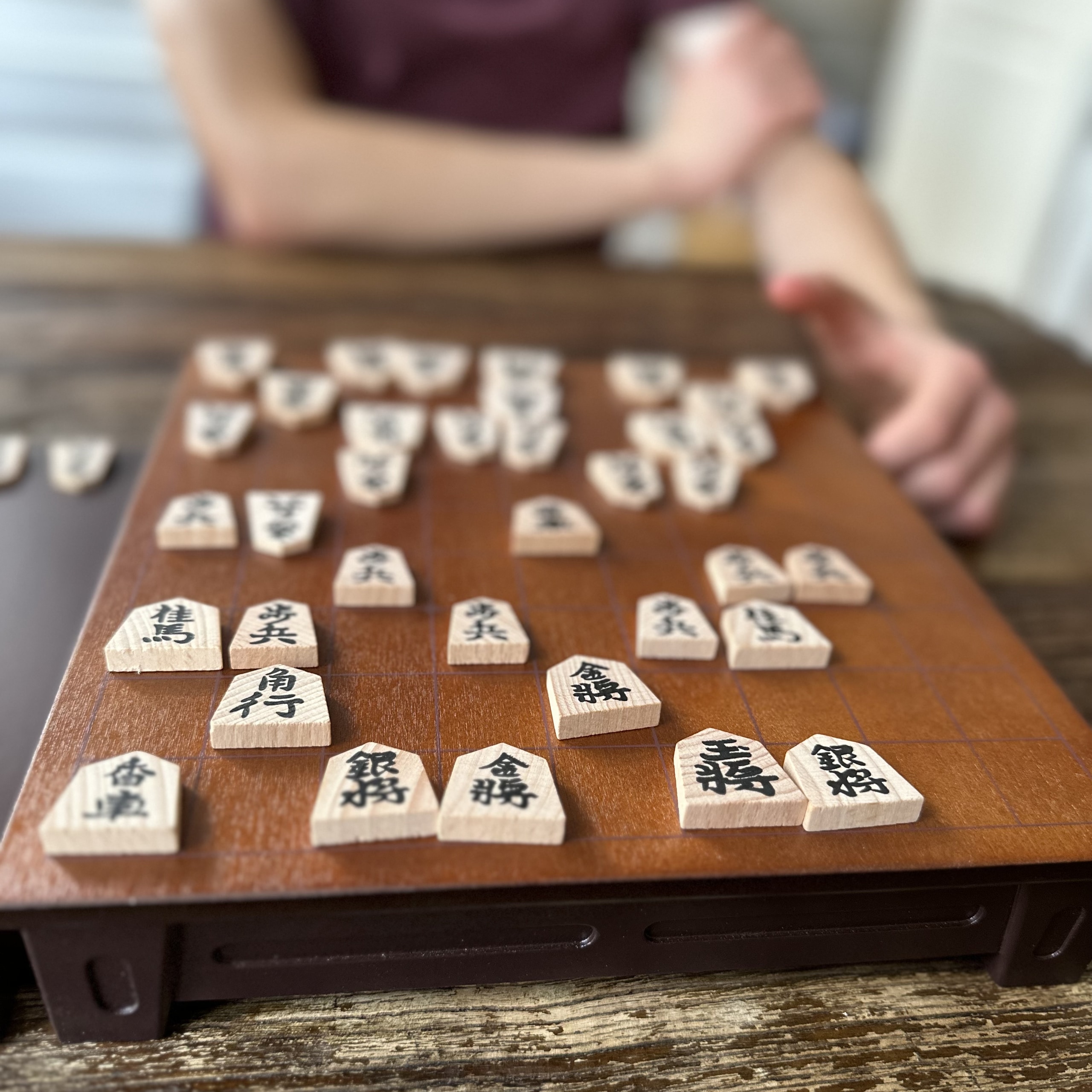 Dark brown shogi board, light wood pieces on the board.