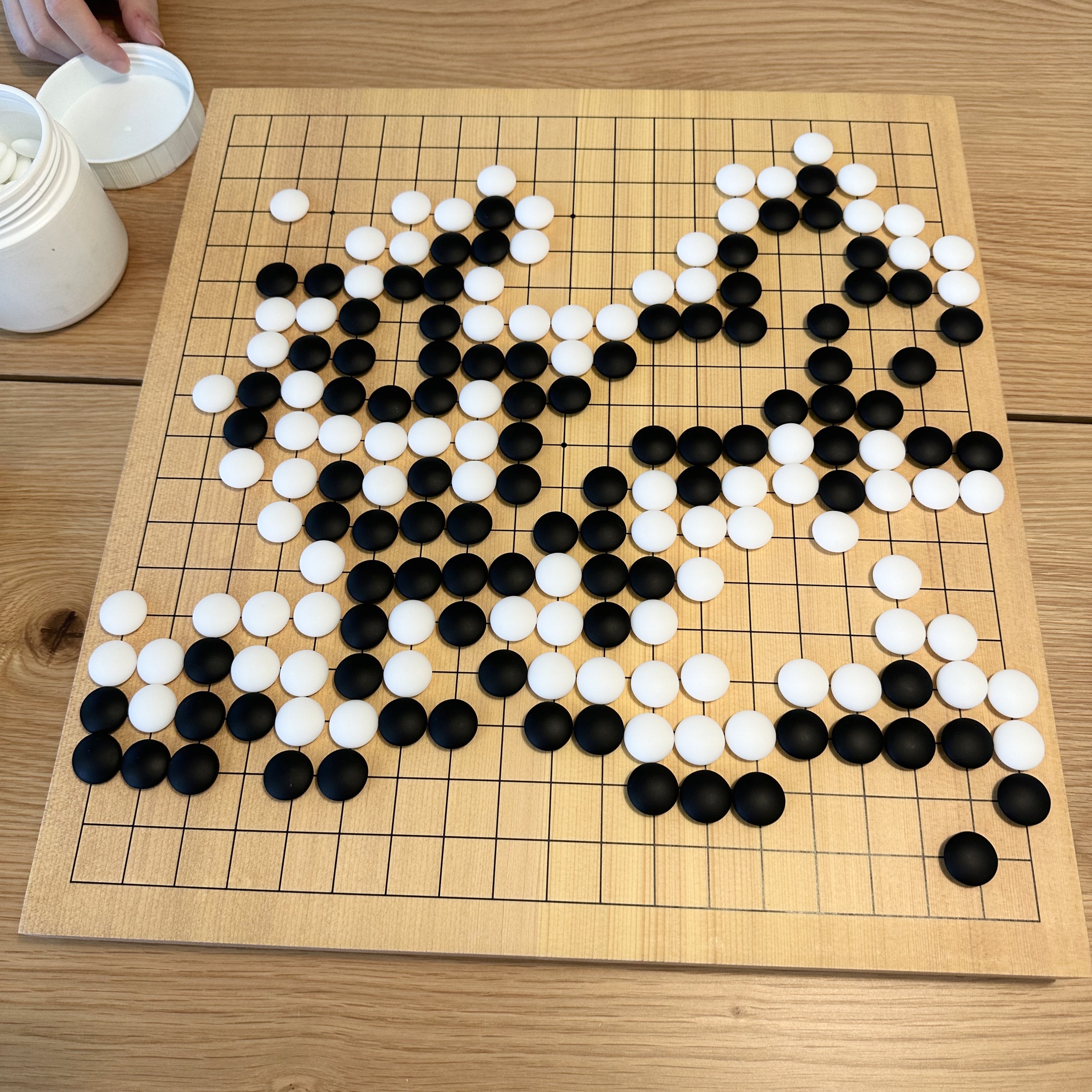 A game of go developing on a wooden board.