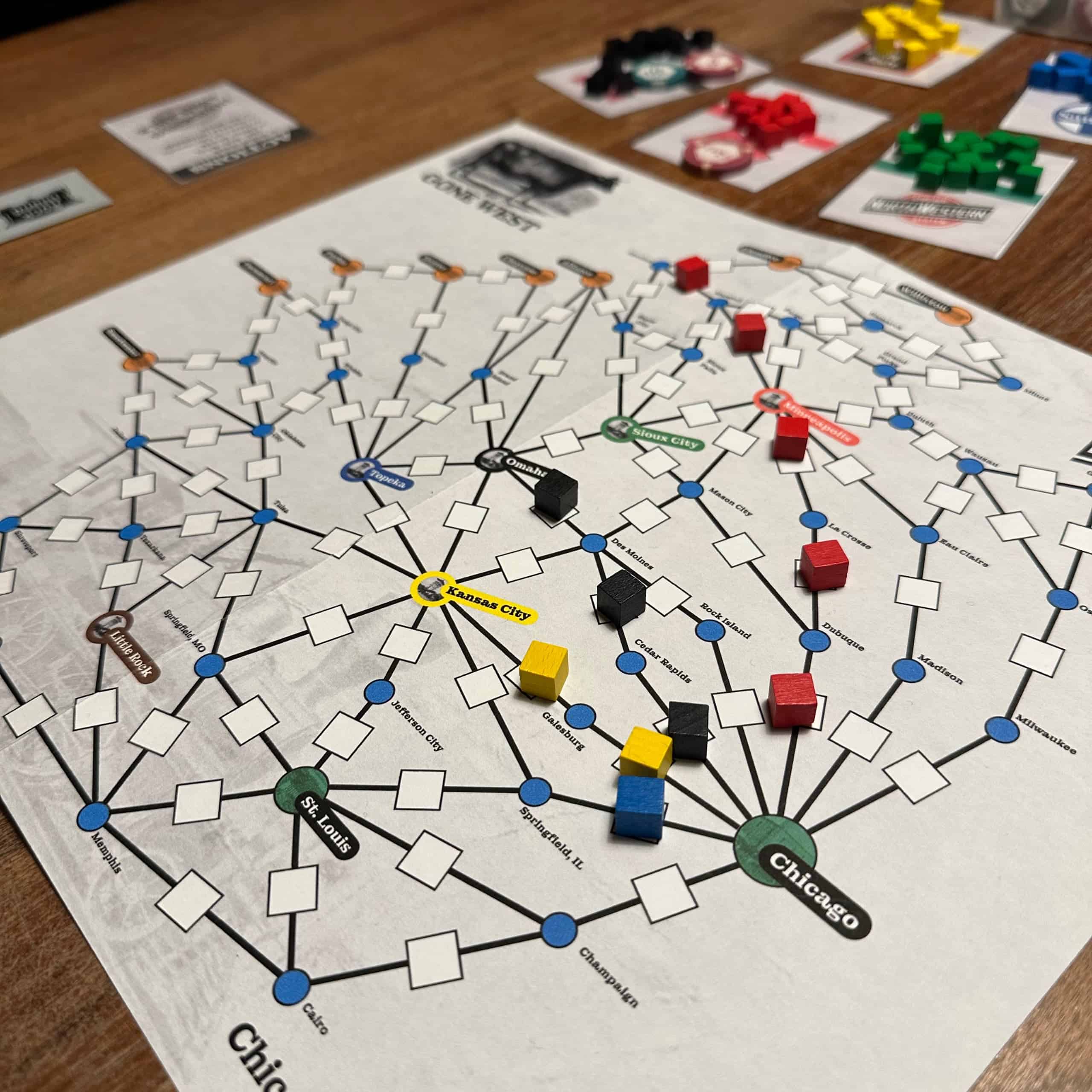 Chicago & NorthWestern board is an abstract representation of railroad lines heading west from Chicago. The board has some coloured cubes depicting the built railroad track. There's a long red line stretching from Chicago to the western edge of the board, and smaller blue, black and yellow lines.