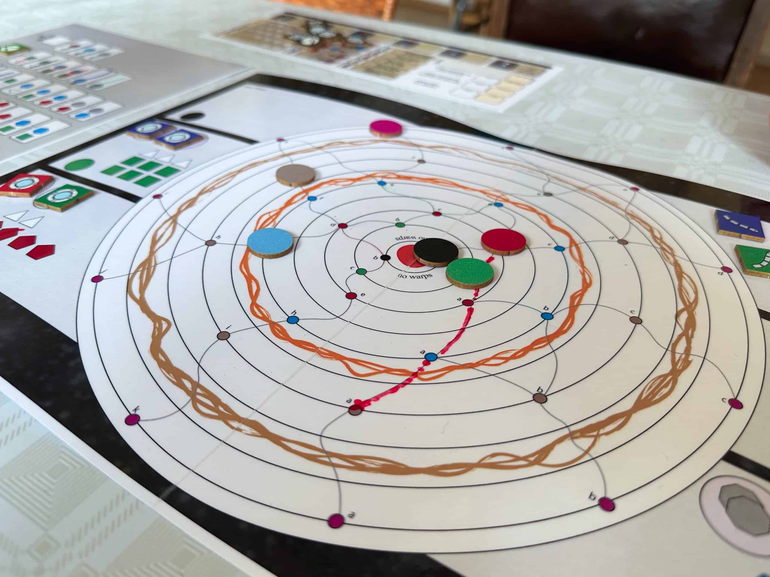 Rayroads board depicts a circular solar system, with a star in the middle and six planets on orbits. Red player is leaving the third planet from the sun to the sixth planet, crossing the radiation zone. This is marked on the board with a dry-erase pen.